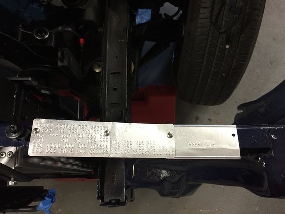 Close-up of a VIN plate and a prep line tag attached to a vehicle frame