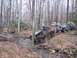 1978 Ford Bronco - Off-road vehicles traverse a stream bed in a wooded area during an outing.