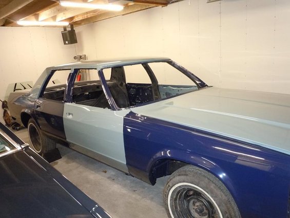 Car in garage, doors and roof removed, primer gray and blue paint