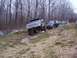 1978 Ford Bronco - Several off-road vehicles, including a 1978 Ford Bronco, tackle a challenging rocky path through a forest.