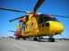 1986 Argo Response - A bright yellow helicopter sits on the ground, its rotors extended against a clear blue sky.