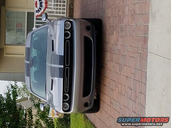 Silver Dodge Challenger with black racing stripes parked on brick driveway