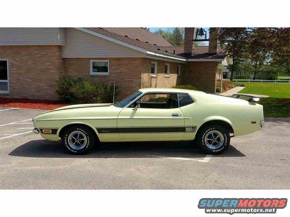 Pale yellow 1971 Ford Mustang Mach 1 parked outside a brick building