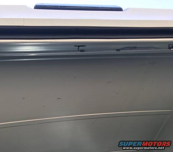Close-up of a vehicle's interior roofline and upper door panel, showing a sunroof and trim