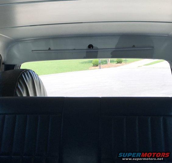 Black vinyl rear seat and spare tire cover inside a vehicle, view through rear window
