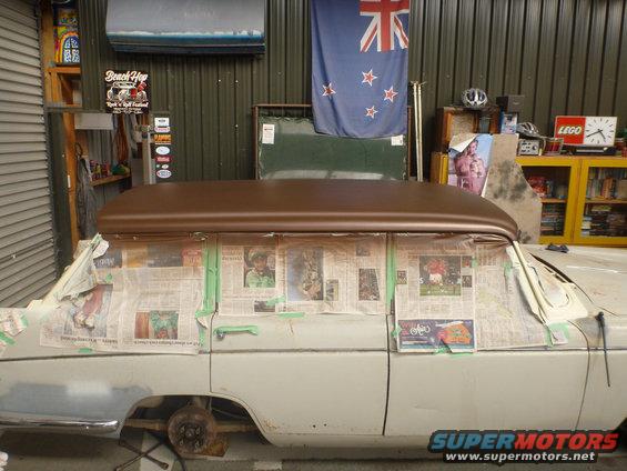 Car with windows covered in newspaper, brown roof installed, in a garage