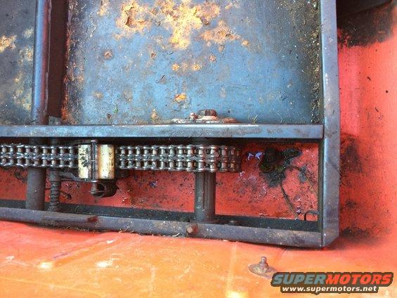 Rusty chain drive mechanism with blue and orange painted metal surfaces