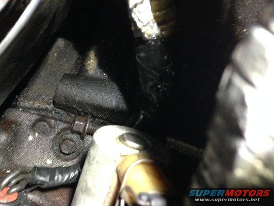 Engine block with bolt and metal bracket. Gloved hand visible