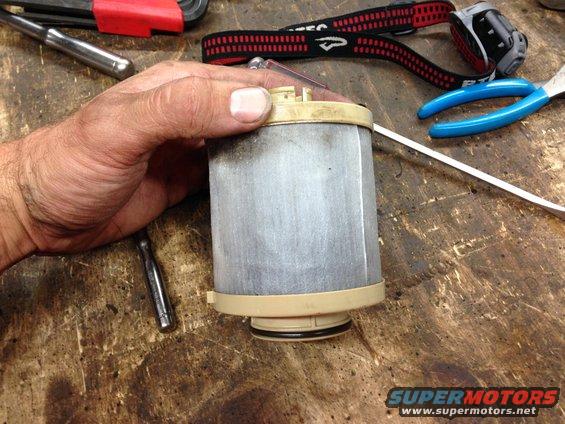 Fuel filter part held by hand, with tools on workbench