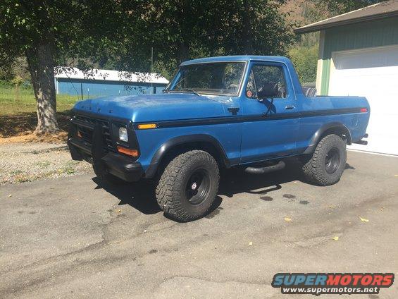 Blue 1979 Ford Bronco parked in a driveway next to a garage