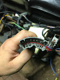 Hand holding a wiring harness connector with exposed wires
