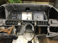 Gray dashboard with gauges and vents removed, wires exposed