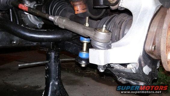 Close-up of a car's tie rod end and sway bar link, supported by a jack stand