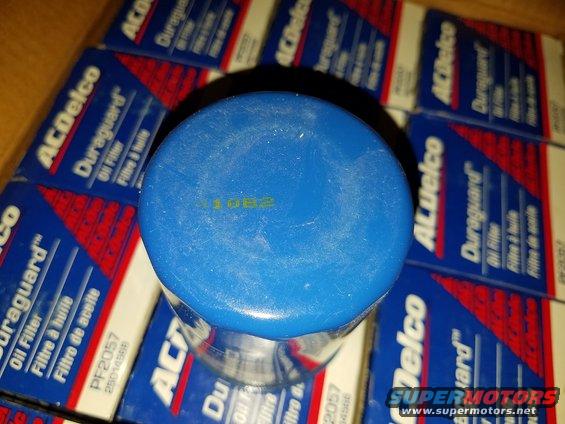 Blue ACDelco oil filter with yellow date code 1082 on top, surrounded by boxes of ACDelco Duraguard oil filters