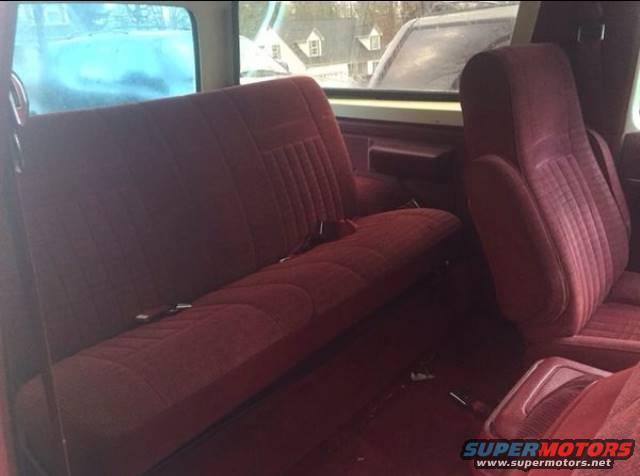 Red interior of a 1988 Ford Bronco with bench and bucket seats