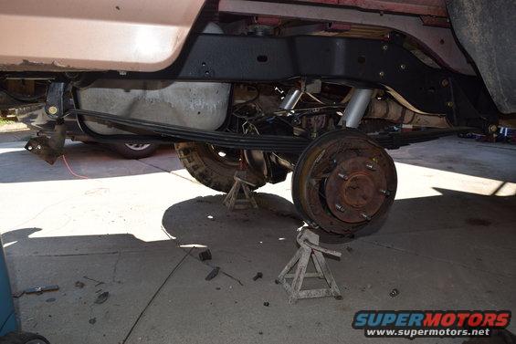 1995 Ford Bronco rear axle assembly with leaf springs and shocks removed, vehicle supported by jack stands