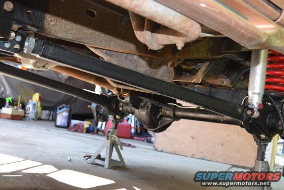 Undercarriage view showing suspension, axle, and exhaust components. Vehicle is on jack stands