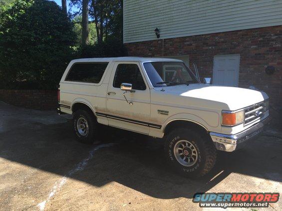 White Ford Bronco parked in driveway, driver's side visible, front quarter view