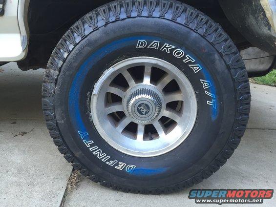 Close-up of a tire with blue lettering and a silver multi-spoke wheel