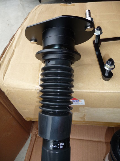 black car suspension strut with bellows and adjustment markings