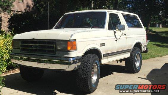 1988 Ford Bronco parked on a paved driveway in front of a house