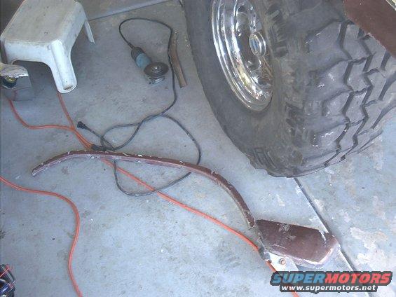 Vehicle part on floor next to tire and angle grinder