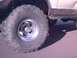 1979 Ford Bronco - A close-up view focuses on the aggressive tread of a large off-road tire mounted on a shiny chrome wheel.