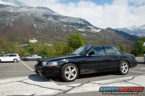 2003 Mercury Marauder parked in a lot, mountains behind it. Another white SUV and silver SUV are also parked
