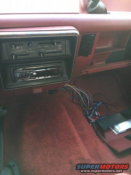 Car interior with aftermarket stereo installed and wires exposed near the center console