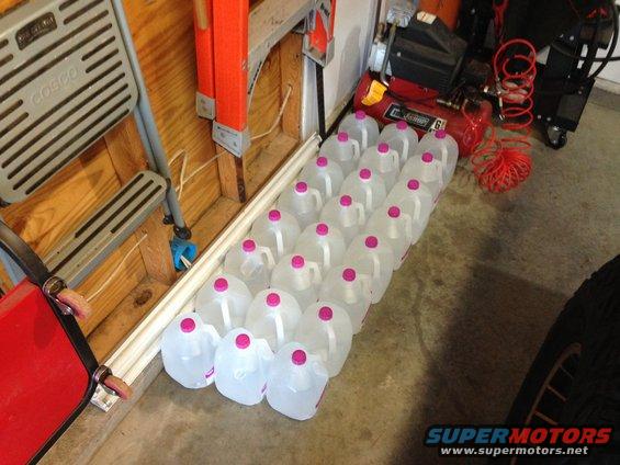 Rows of plastic jugs with pink caps on a concrete floor