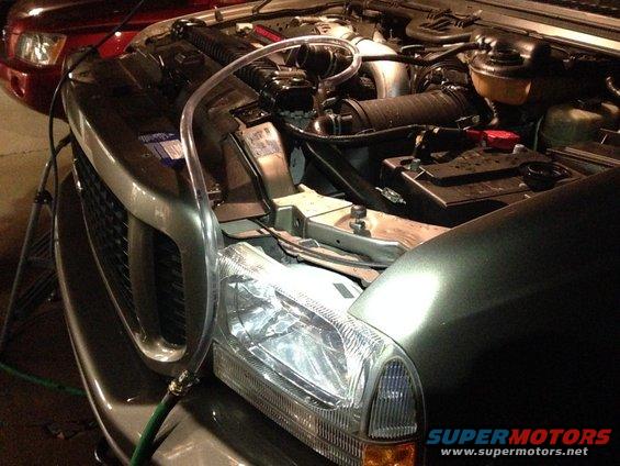 2003 Ford Excursion engine bay with a clear tube connected to the radiator overflow