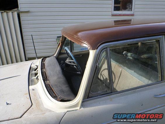 Car interior with brown roof, showing steering wheel and dashboard area. The windshield is missing