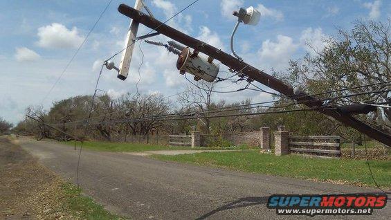 Fallen utility pole with transformer and wires across a rural road