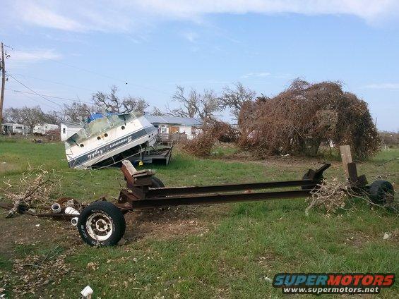 Boat named 'Summer Nights' overturned on a trailer next to a damaged trailer frame