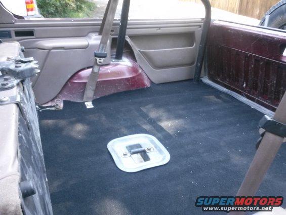 1996 Ford Bronco interior cargo area with black carpet and a metal access panel