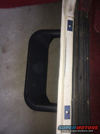 Black step with a logo on it, next to a white trim piece with blue accents