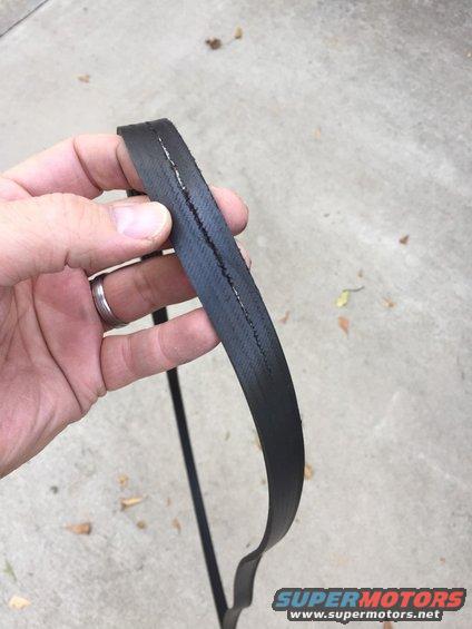 Hand holding cracked black serpentine belt