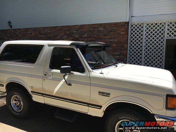 White Ford Bronco parked in front of a brick and white siding building