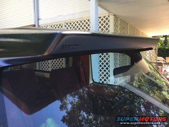 Dark rear spoiler with embossed text above rear window of an SUV