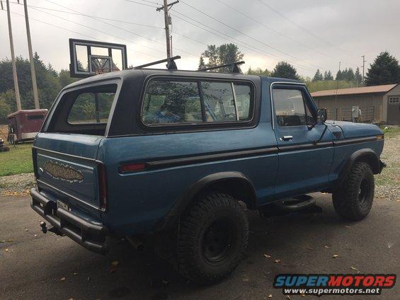 Blue Ford Bronco, 3/4 front view, with aftermarket bumper and roof rack. Basketball hoop visible in background