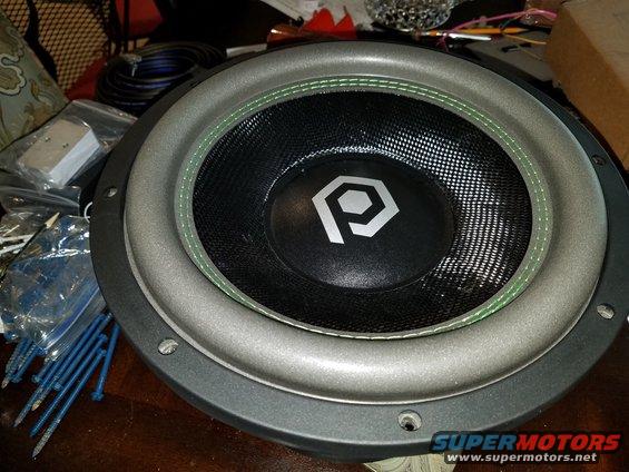 Subwoofer with a silver surround and black cone, a hexagonal 'P' logo