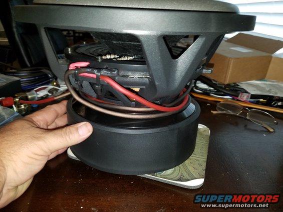 Car subwoofer with red and black wiring, held by a hand