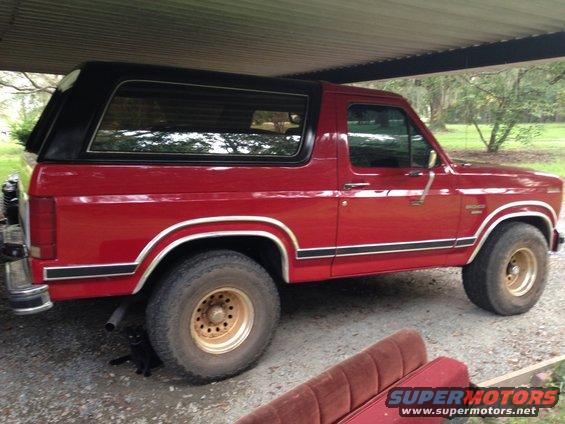 Red 1986 Ford Bronco side view with black top