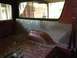 1986 Ford Bronco - The interior of a red SUV shows diamond plate paneling and a worn cargo floor.