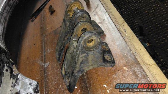 three rusty metal brackets on a wooden surface
