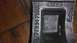 1996 Ford Bronco - A black metal part with stamped markings is shown close-up against a wooden background.