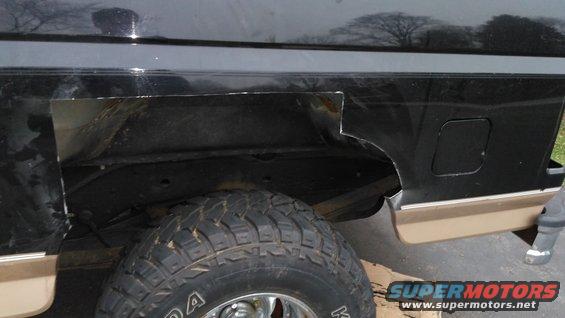 Black SUV rear quarter panel with cut-out section, tan lower trim, and off-road tire