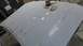 1996 Ford Bronco - Body filler is applied and sanded on a car hood in a workshop.