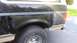 1996 Ford Bronco - The rear section of a dark-colored SUV with tan trim displays signs of wear and tear, including rust spots.