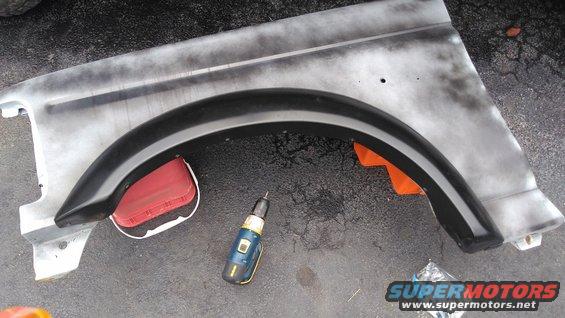 Gray fender with black trim and red reflector, a drill sits nearby